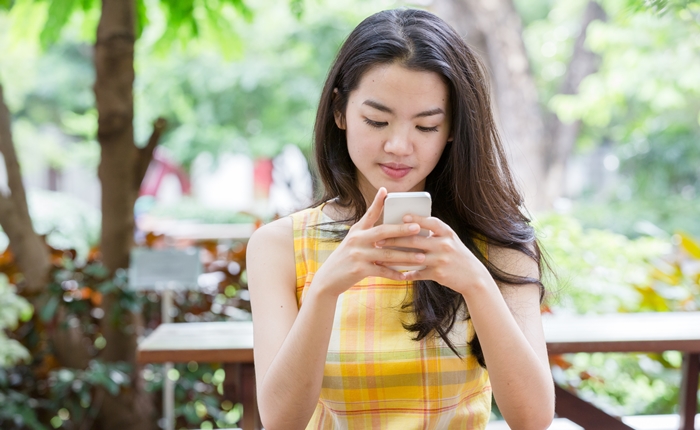 Young asian woman happily using a smart phone