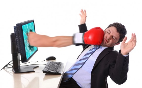 Business man in stress with computer hit by boxing glove