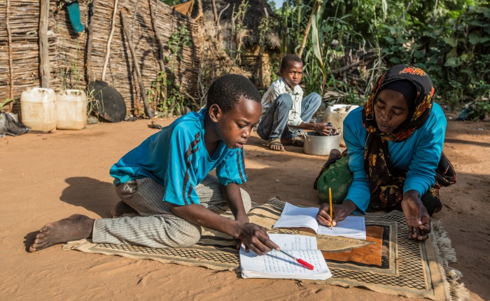 Chad. Refugee mother and her children study together