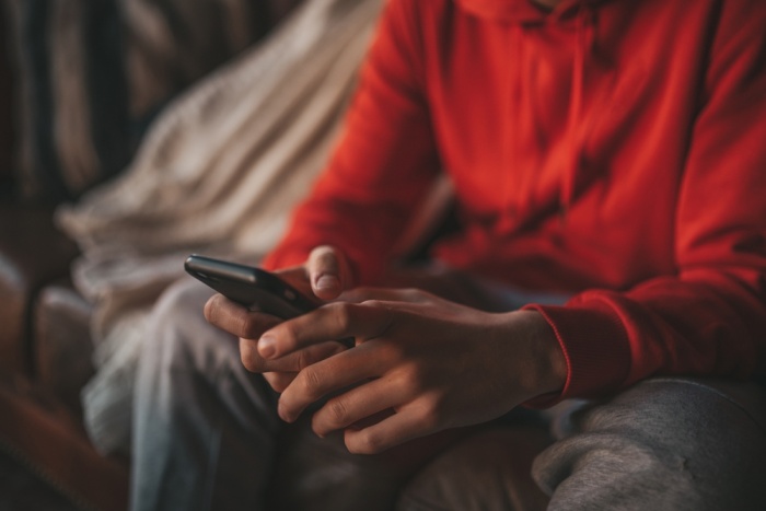 Young,Teen,Boy,With,Long,Hair,Holding,Smartphone,Using,Wireless